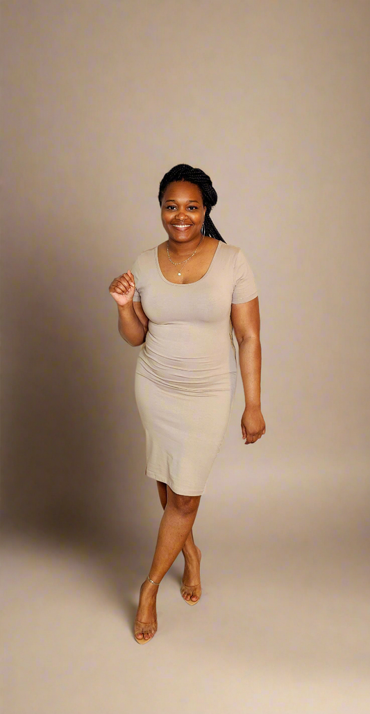 A woman standing in a studio setting, wearing a beige, premium cotton short sleeve classic midi dress with a crew neck.