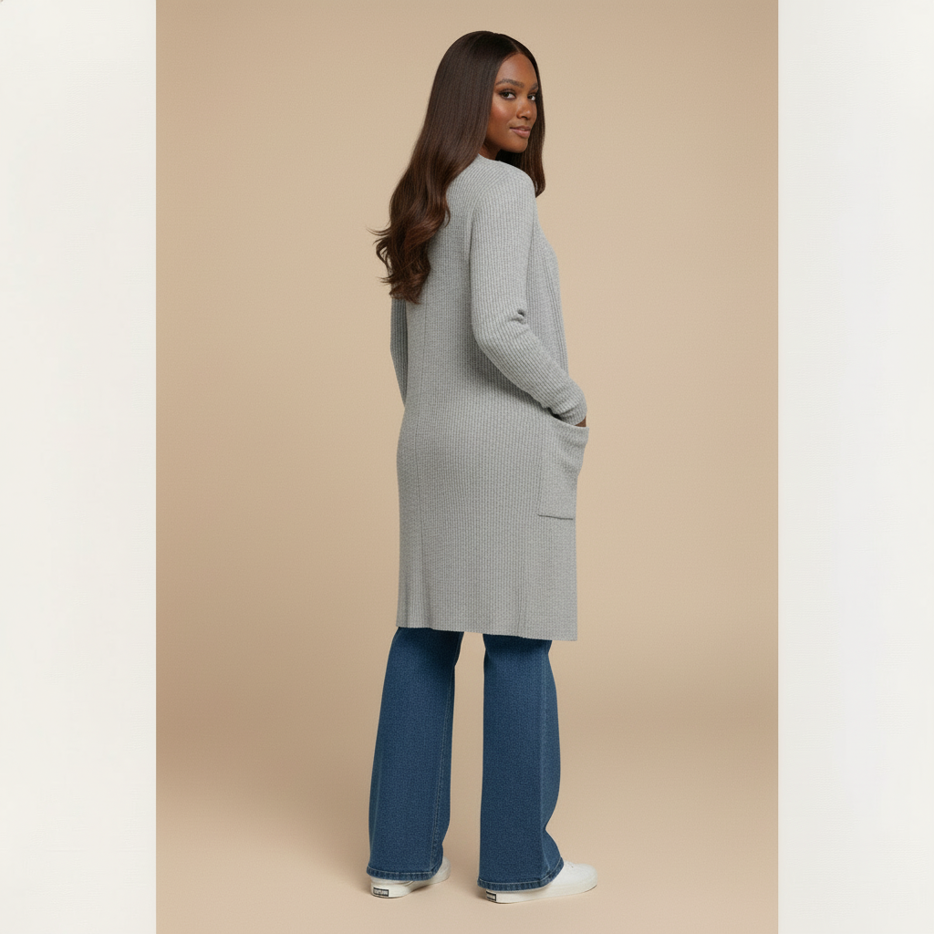 Woman wearing a long gray cardigan and blue jeans on a beige background