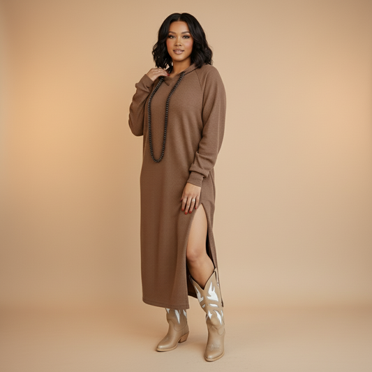 Woman wearing a brown dress with a slit and metallic boots on a beige background